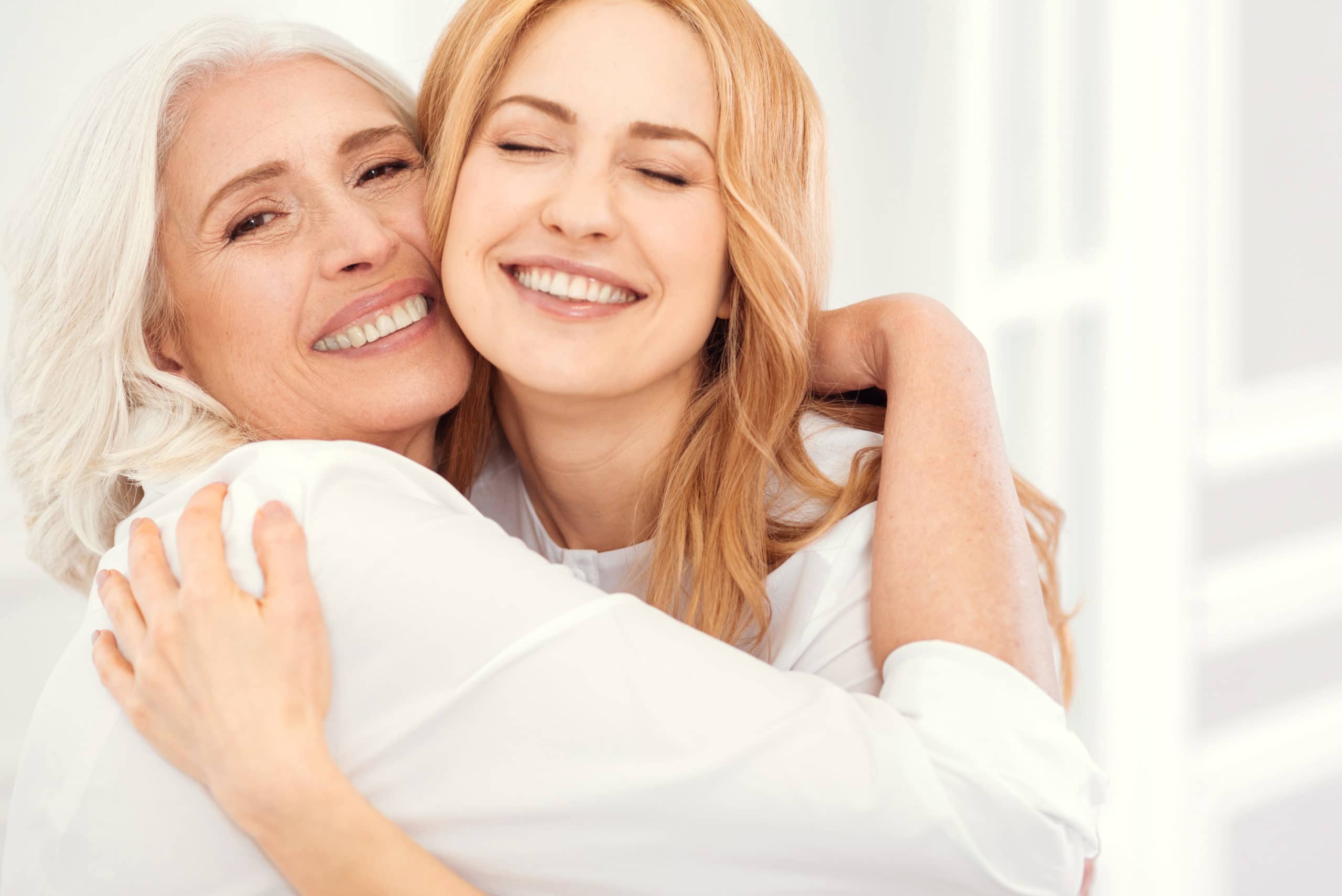 Radiant mother and daughter beaming into camera while hugging