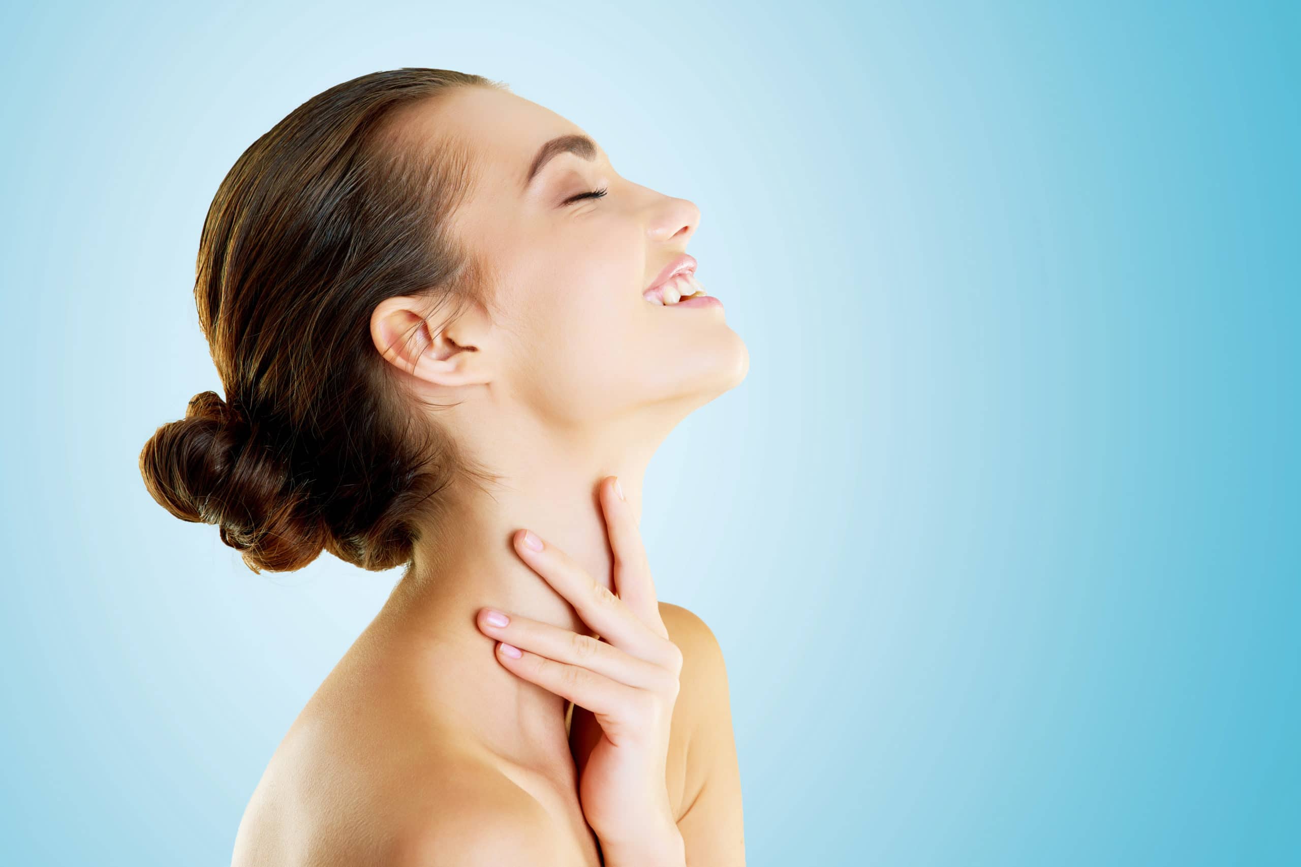 Shes been given the gift of beauty. Studio shot of a beautiful young woman feeling her skin against a blue background.